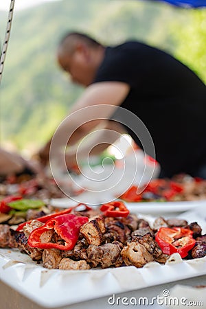 an Asian man in a black shirt cooks a barbecue in nature Stock Photo