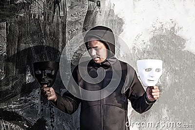 Asian man chooses between black and white mask in scary abandoned building, Human face expression, Good and Bad temptation Stock Photo