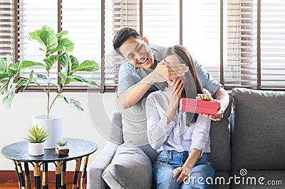 Asian man giving a gift box present to surprise his girlfriend at home Stock Photo