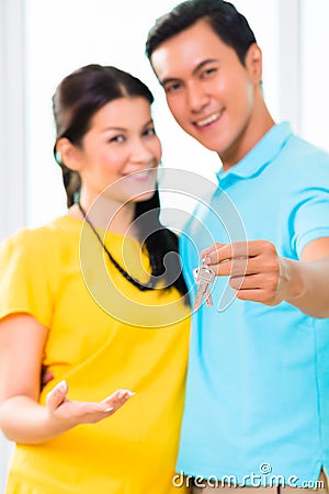 Asian man giving girlfriend key to move in new home Stock Photo