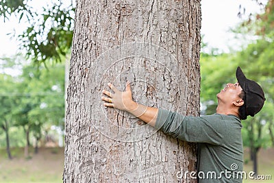 Asian man giving a hug on big mango tree. Take care the earth, Love tree and nature or environment concept Stock Photo