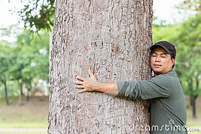 Asian man giving a hug on big mango tree. Take care the earth, Love tree and nature or environment concept Stock Photo