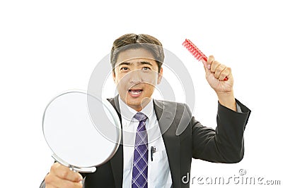 Asian man holding hand mirror with hairbrush Stock Photo
