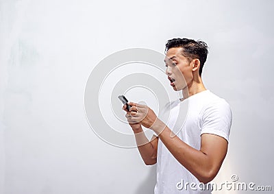 Asian man holding smartphone and surprised by notification on his smartphone about discount or cash back from online shop Stock Photo