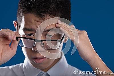 Asian man with a terrible headache. Portrayed on a blue backgrou Stock Photo