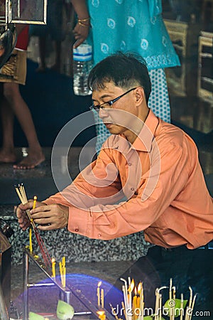 Asian man lighting candles in the temple. Religious ceremony in the temple. Local people of Asia. Editorial Stock Photo