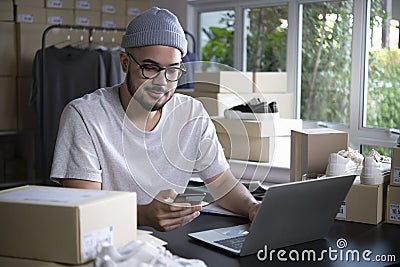 Asian man online seller confirming orders from customer on the phone. E-commerce male business owner looking at the phone in store Stock Photo