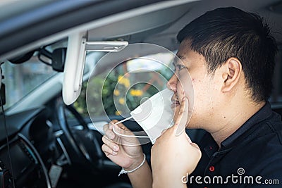 Asian man with pimple on skin,look at inflamed acne spot in front of a mirror,male pointing at acne on cheeks under face mask,skin Stock Photo