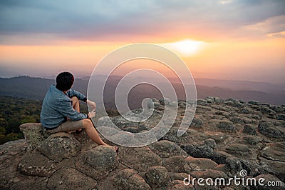 Asian man sitting on Nodule rock field enjoy looking sunset Stock Photo