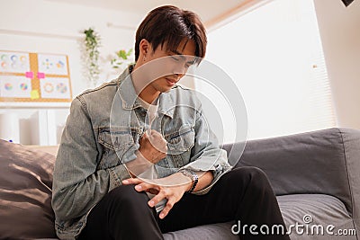 Asian man suffered a heart attack, resulting in chest pain and illness on the sofa Stock Photo