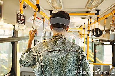 Asian man taking public transport, standing inside bus. Stock Photo