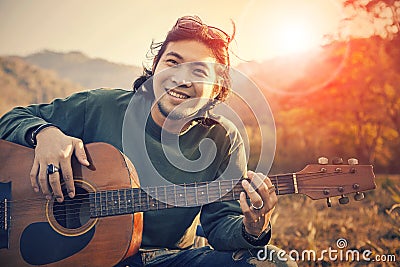 Asian man toothy smiling face with happiness playing guitar and Stock Photo