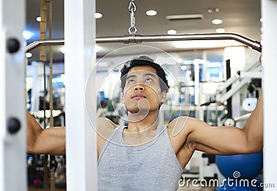 Asian man using lat pulldown machine Stock Photo