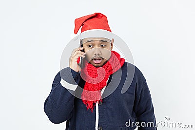 Asian man weared blue sweater, santa hat, red scarf using mobile phoe calling Stock Photo