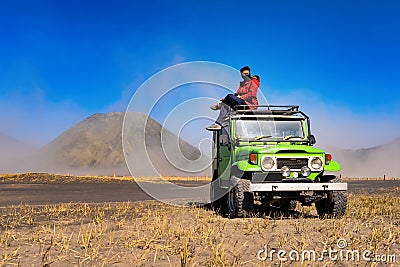 An Asian man wearing mask and sitting on jeep car at Mount Bromo. An active volcano, one of the most visited tourist attractions, Stock Photo