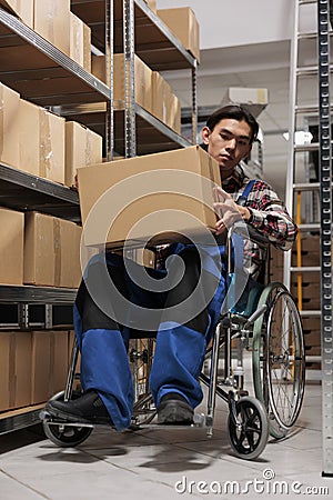 Asian man wheelchair user carrying parcel in postal warehouse Stock Photo