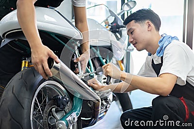 Asian mechanic man fixing the retro motorcycle in the garage. Film effected - Selective focused Stock Photo