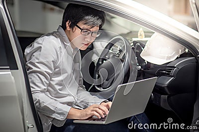 Asian mechanical engineer working with laptop in the car Stock Photo