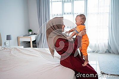 Asian moslem mother holding her little boy on lap when playing together Stock Photo
