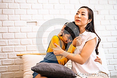 Asian mother comforting crying teenage daughter in miserable, stressed, depressed, sad state of mind Stock Photo