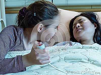 Asian mother and daughter laying in hosital bed, child pressing nurse call button Stock Photo