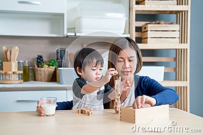 Asian mother enjoy to play wooden jigsaw puzzle together in area of kitchen of their house and they look happiness Stock Photo