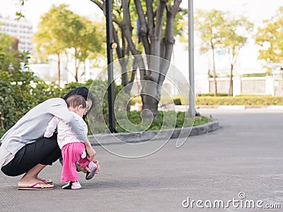 Asian mother help toddler wearing shoes. Stock Photo