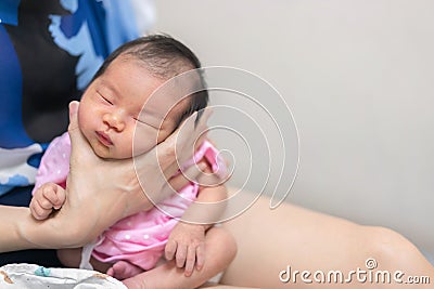 Asian mother hold tiny newborn baby with hand for help infant belch after breastfeeding milk to heal gas pain or indigestion, Stock Photo