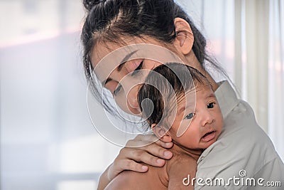 Asian mother holding her cute infant baby boy on her shoulder Stock Photo