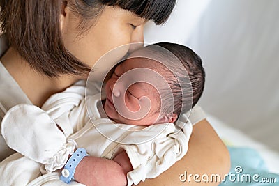 Asian mother kissing her newborn baby Stock Photo