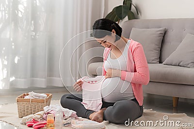 Asian mother preparing little clothes for new baby when sitting on the floor Stock Photo