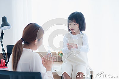 Asian Mother is teaching daughter wash hands with alcohol gel sanitizer Stock Photo
