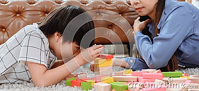 Asian mother work home together with son. Mom and kid play color wooden block. Child creating building toy. Stock Photo