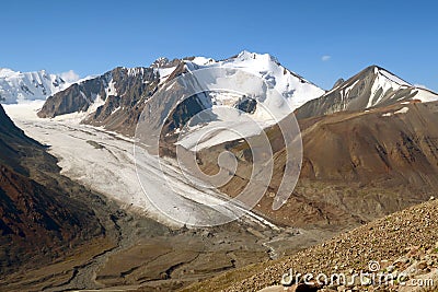 Asian mountains: high peak with rocks and summit covered by snow and a giant glacier that gives rise to river Stock Photo