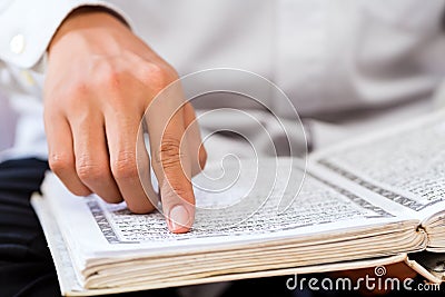 Asian Muslim man studying Koran or Quran Stock Photo