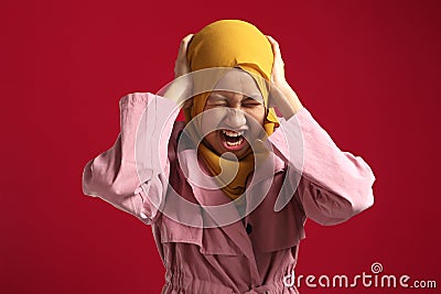 Asian muslim teenage girl wearing hijab, screaming losing temper, cant control emotions, close eyes and ears while yelling Stock Photo