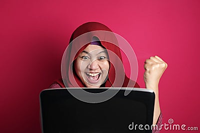 Asian Muslim women using hijab look surprised and happy to see good news on her laptop Stock Photo