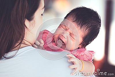 Asian newborn baby girl crying with tried on mother`s shoulder Stock Photo