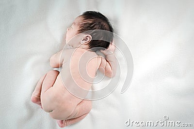 Asian newborn baby lying asleep on white blanket. Stock Photo