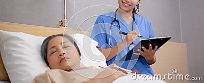 Asian nurse check saline and check patient elderly while asleep on bed at hospital ward, doctor diagnostic senior. Stock Photo