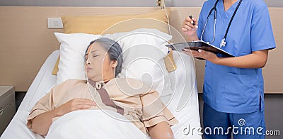 Asian nurse check saline and check patient elderly while asleep on bed at hospital ward. Stock Photo