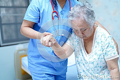 Asian nurse physiotherapist doctor care, help and support senior or elderly old lady woman patient get up from bed at hospital war Stock Photo