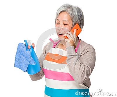 Asian old housewife talk to cellphone and usinf rag and bottle s Stock Photo