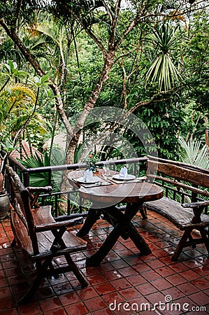 Asian outdoor living area with wooden benches and table in trop Editorial Stock Photo