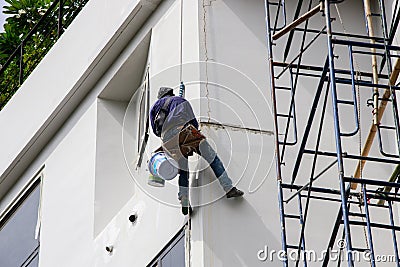 Asian Painter hanging by rope for fixing and painting exterior building wall Editorial Stock Photo