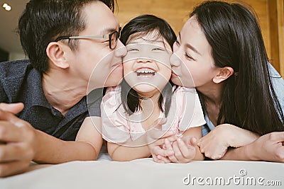 Asian Parents kissing their little daughter on both cheeks. family portrait. Stock Photo