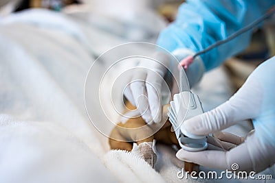 Asian patient`s hand with an attached pulse oximeter on finger for monitoring,doctor measuring pulse rate and oxygen saturation, Stock Photo