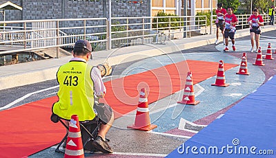 Asian photographer taking picture of charity marathon participants group o coastal bridge while running to finish line Editorial Stock Photo