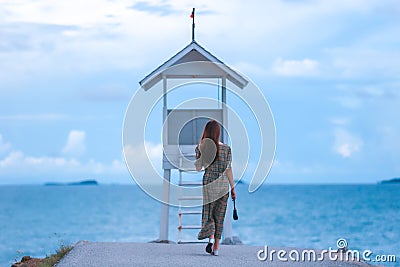 Asian pretty gilr wearing dress so alone feeling with walking and sit on walk way to to sea on evening Stock Photo