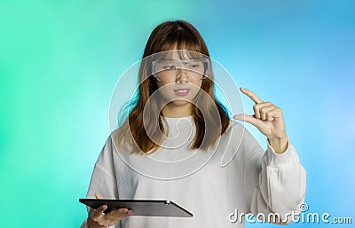 Asian pretty woman in white long sleeve t shirt wearing vr glasses holding tablet connecting with virtual world, augmented reality Stock Photo